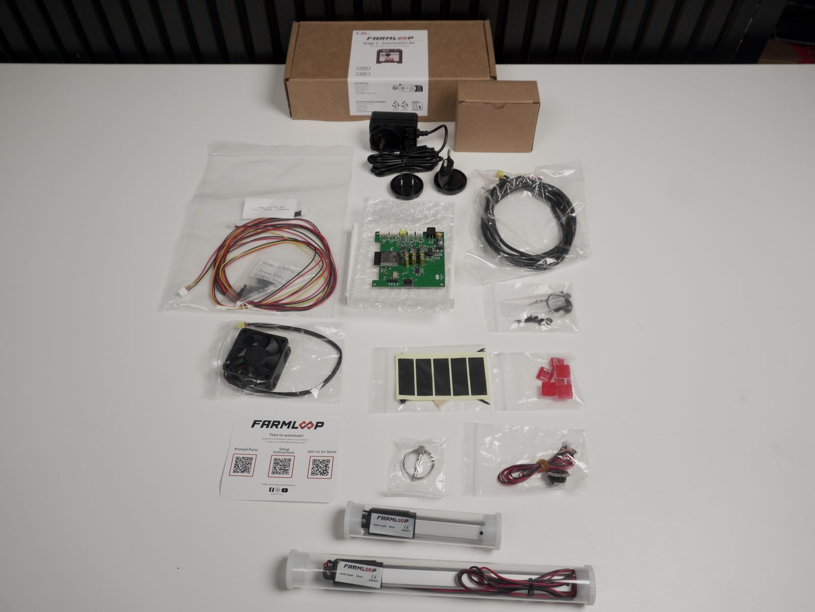 FarmLoop Stage 2 kit contents laid out: box, power supply, FarmBoard PCB, actuators, fan, and hardware