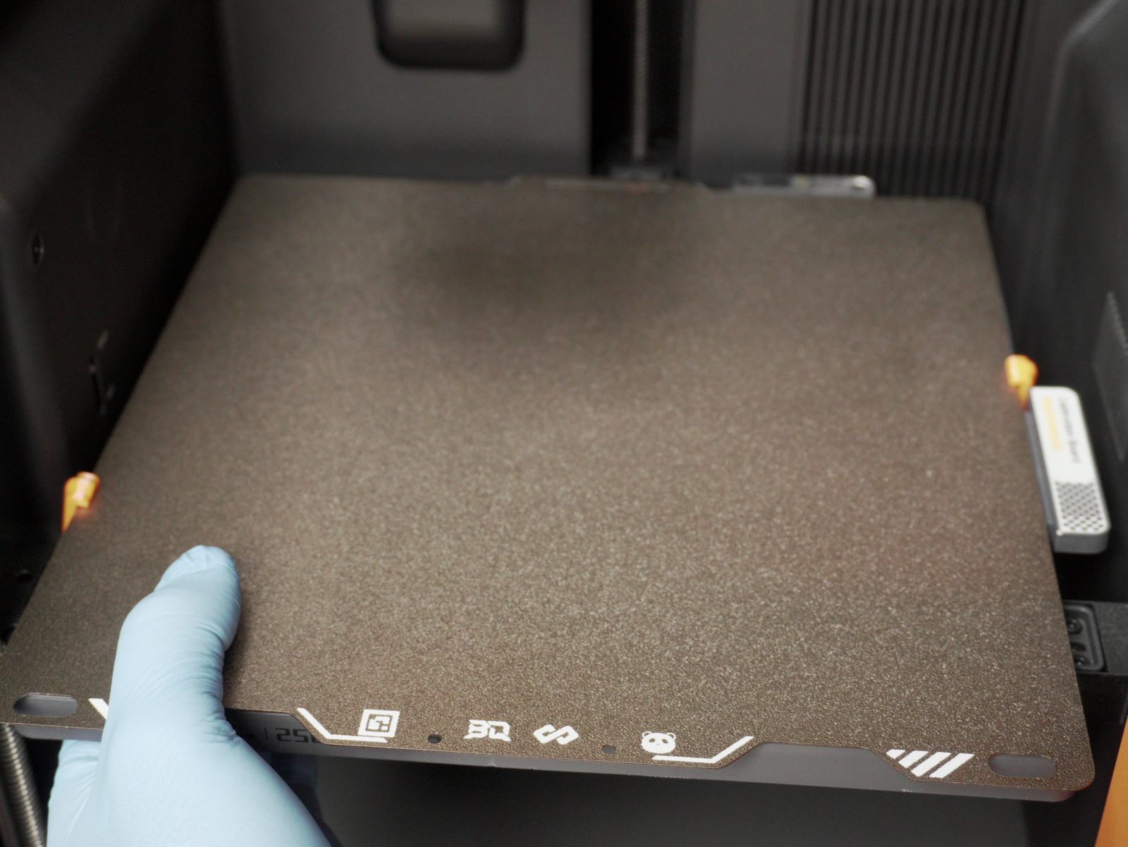 Build plate being seated on the printer with its corner clips visible