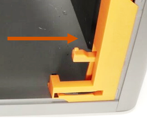Orange bender bracket positioned at the printer corner, arrow showing the insertion direction