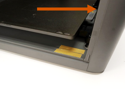 Top-down view of the printer frame with the double-sided tape strip highlighted by an arrow