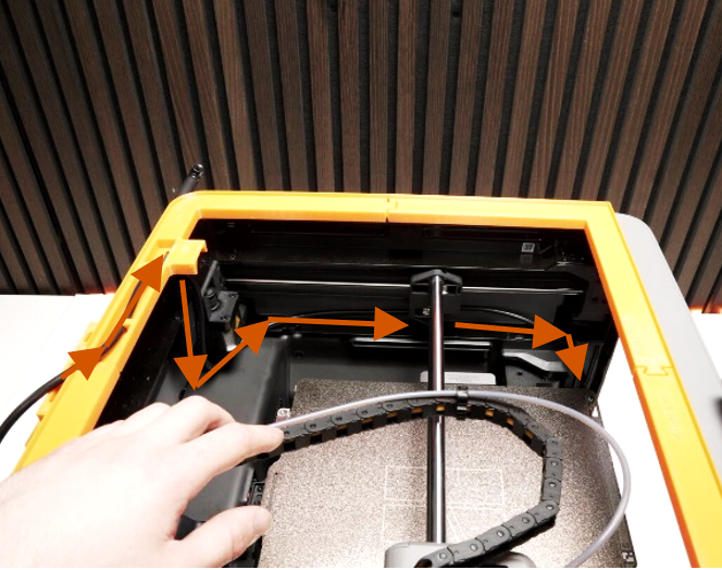 Top-down view of the printer interior with arrows showing the cable routing path